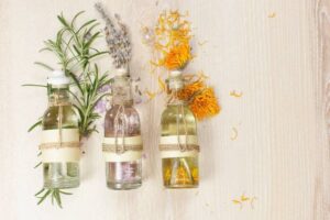 Essential oils for aromatherapy and massage. Row of essential oils in glass bottles, rosemary, lavender and calendula, on the wooden board.